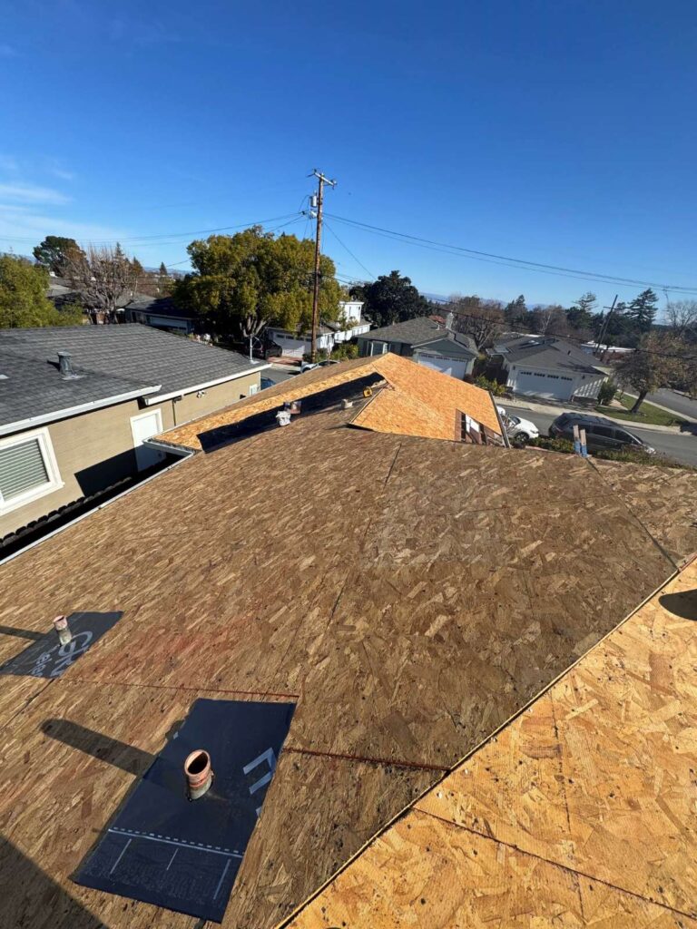 Residential roof replacement showing new plywood sheathing installed before underlayment and shingles.