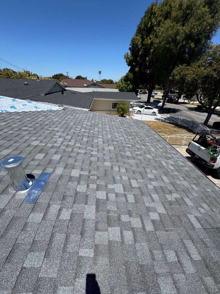 New gray asphalt shingle roof with metal vent installed on a residential home.