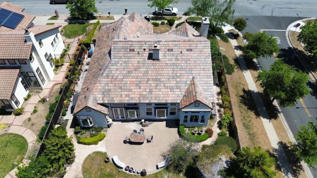 Aerial view of a residential home with newly installed multi-colored tile roof and backyard patio.