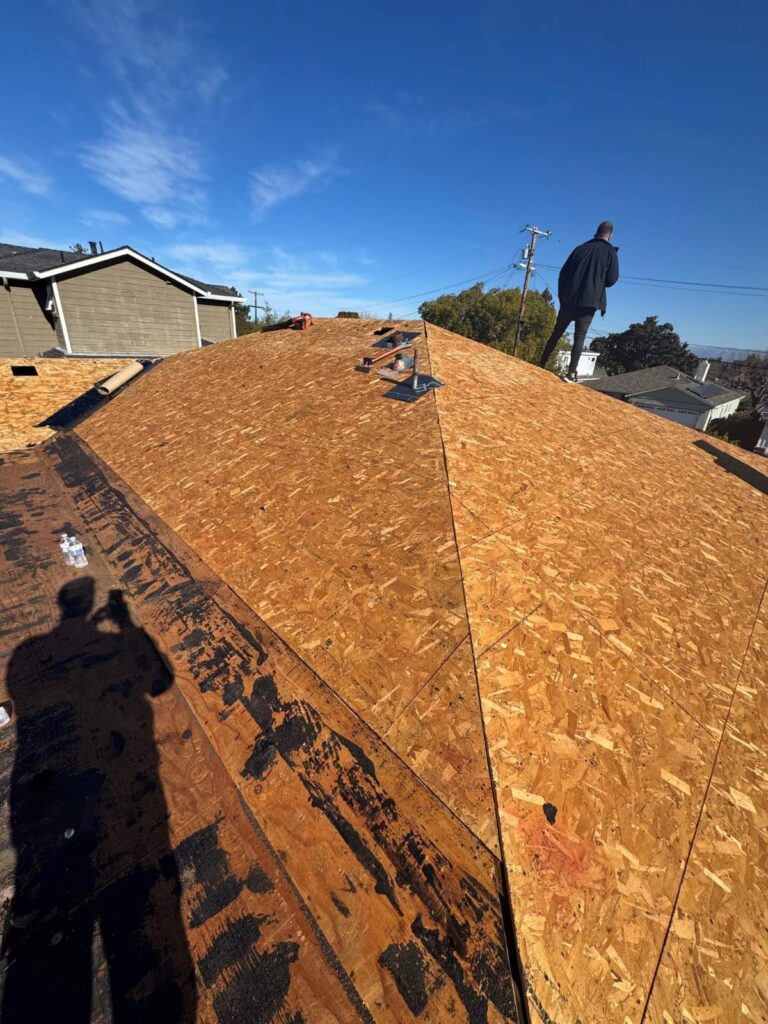 Roof replacement in progress with new plywood sheathing installed on a residential home before shingles are added.