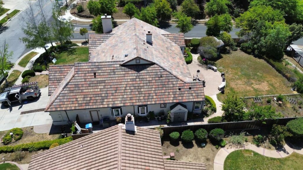 Aerial view of a completed residential roof with new multi-colored tile installation on a suburban home.